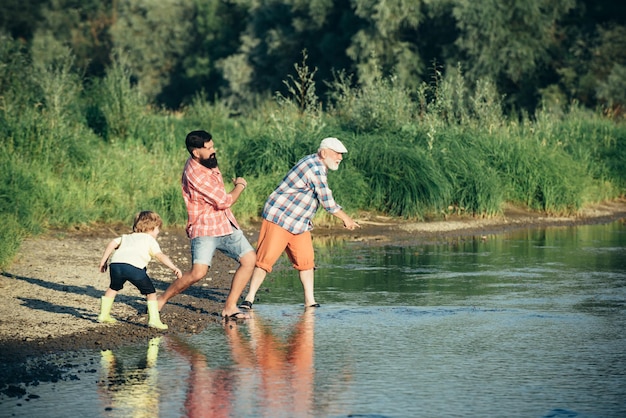 Día del padre Padre enseñando a su hijo a saltar piedras Familia de tres generaciones Generación de personas y etapas de crecimiento