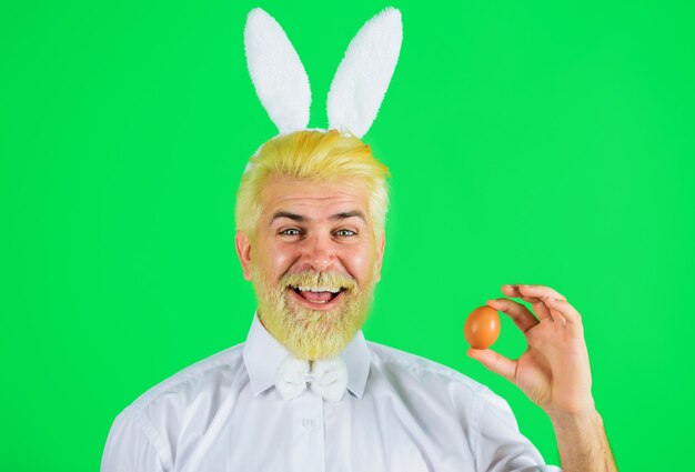 Foto día de pascua, feliz hombre barbudo con orejas de conejo con huevo de pascua, búsqueda de huevos, conejito.