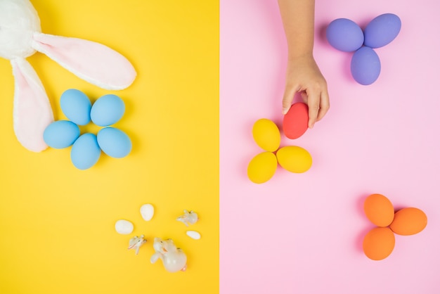 Día de Pascua pequeña oreja de conejo con mano de niño y huevos decorados