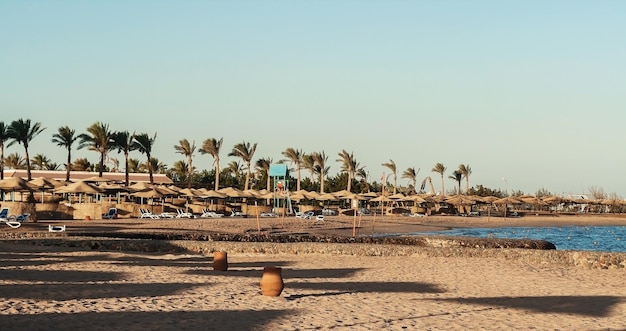 Foto día en la playa sombrillas de paja y tumbonas