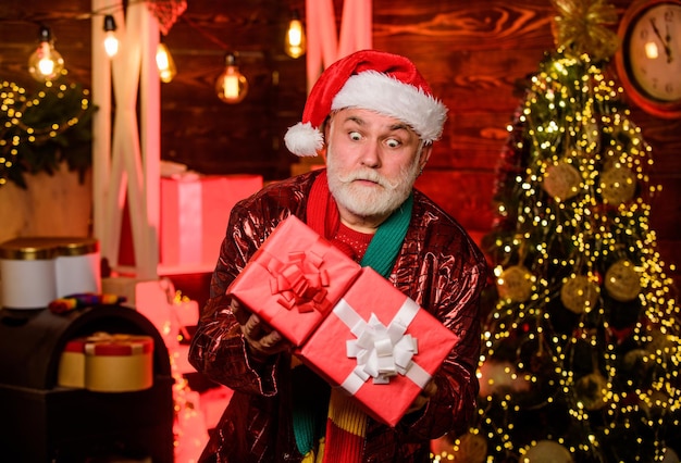 Día de San Esteban. Valores familiares. Celebración de Navidad. Celebración de las vacaciones de invierno. Garland ilumina un ambiente acogedor. Celebración de Año Nuevo. Abuelo con barba blanca y cajas de regalo. Hombre mayor de Papá Noel.