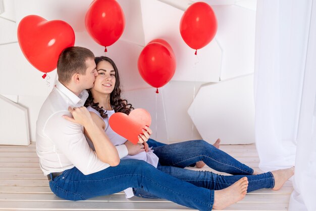 El día de San Valentín, un chico besa a una hermosa chica que sostiene un gran corazón rojo