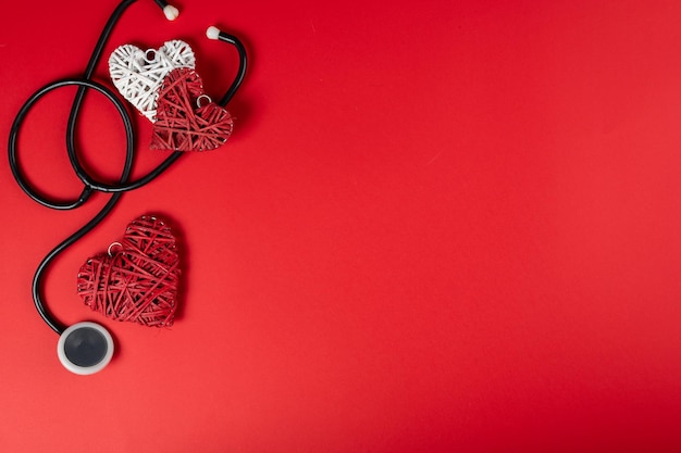 Día de San Valentín y concepto de día más dulce. Estetoscopio con corazón rojo sobre fondo rojo. Símbolo de amor para la salud y el bienestar.
