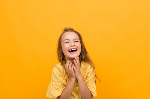 Día de San Valentín y concepto de vacaciones. Atractiva encantadora niña feliz en una camiseta y una falda sonríe muy ampliamente y sinceramente sobre un fondo amarillo