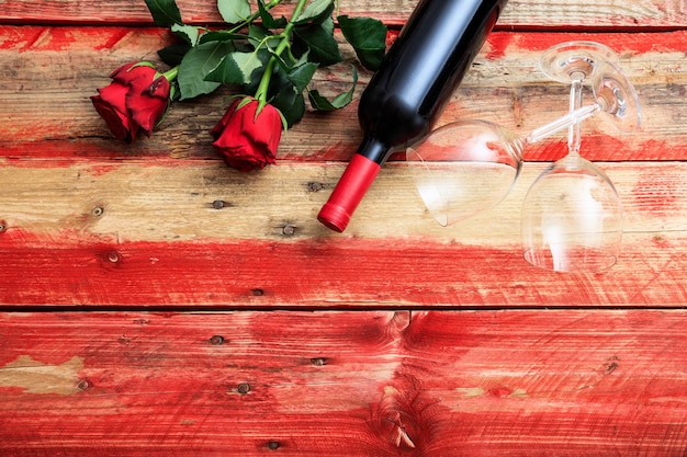 Día de San Valentín Copas de botella de vino tinto y rosas sobre fondo de madera