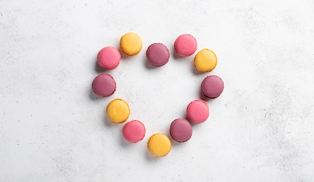 Día de San Valentín corazón hecho de macarons de diferentes colores. Dia de la mujer. Fondo de hormigón blanco, banner