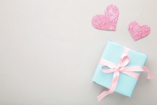 Día de San Valentín con corazones de color rosa y caja de regalo en gris