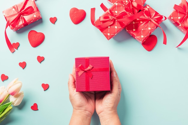 Día de San Valentín y cumpleaños Manos de mujer sosteniendo regalo o caja actual decorada y corazón rojo