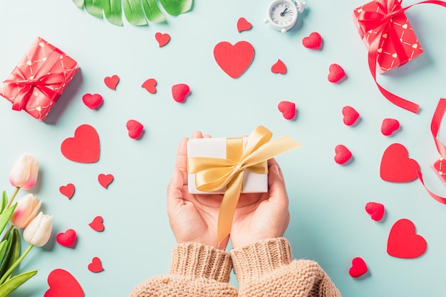 Día de San Valentín y cumpleaños Manos de mujer sosteniendo regalo o caja actual decorada y corazón rojo