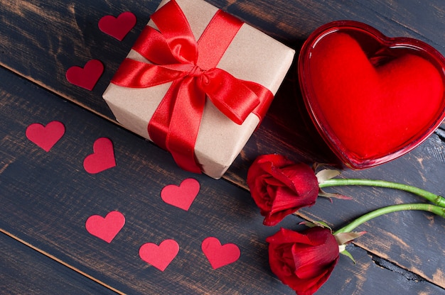 Día de San Valentín. Decoración con caja de regalo, corazones rojos y flores sobre fondo de madera rústica