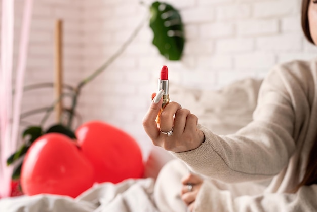 Día de San Valentín, Día de la Mujer. Morena joven caucásica Mujer sentada en la cama haciendo labios para colorear