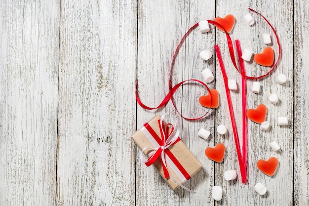 Día de San Valentín dulces corazones malvaviscos y caja de regalos en papel artesanal sobre fondo blanco de madera.