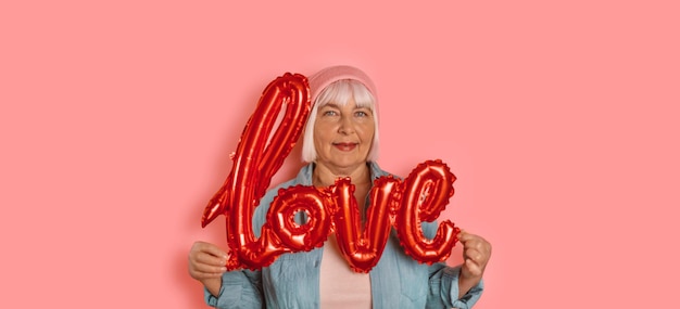 Día de San Valentín con globos de letras de amor brillantes en manos de mujer aisladas sobre fondo de color rosa brillante