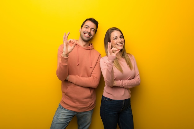 En el día de San Valentín Grupo de dos personas sobre fondo amarillo que muestra un signo aceptable con los dedos