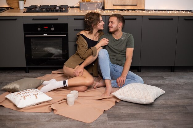 Día de San Valentín. Hermosa joven pareja sentada en el piso de la cocina en casa