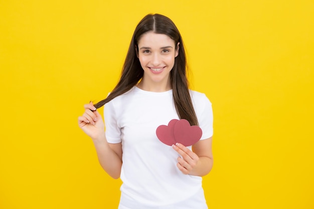 Día de San Valentín Hermosa mujer joven con el corazón en sus manos Mujer atractiva con corazón de papel sobre fondo amarillo