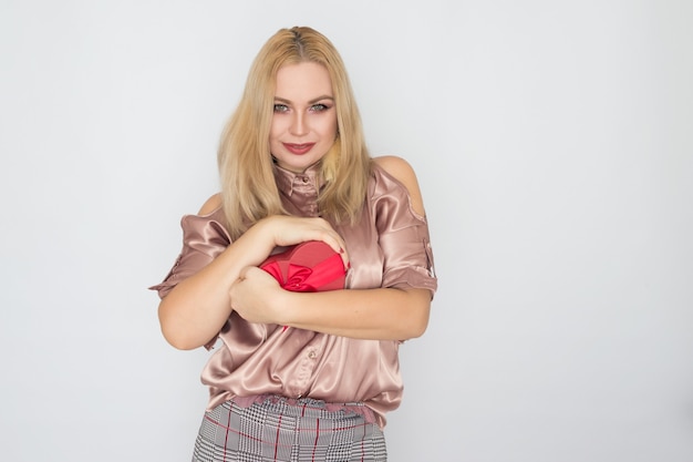 Día de San Valentín - mujer soñando en blusa rosa con corazón de caja de regalo roja