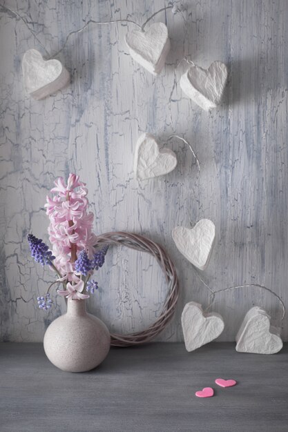 Día de San Valentín o celebración de primavera, florero con flores de jacinto y guirnaldas con corazones de papel