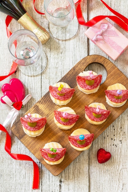 Día de San Valentín o cumpleaños bocadillos románticos Canapés con pan queso salami y aceitunas Vista superior plana