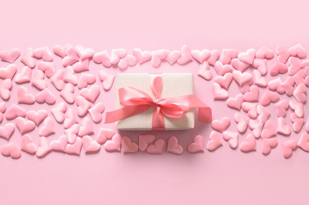 Día de San Valentín o regalo femenino recién nacido y corazones sobre fondo rosa. Tarjeta de felicitación romántica con espacio de copia.