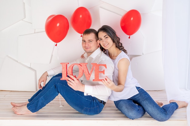 El día de San Valentín, una pareja enamorada sosteniendo un gran cartel de amor.