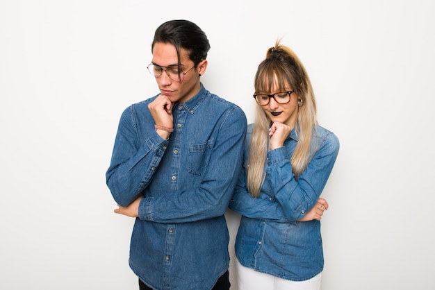 En el día de San Valentín Pareja joven con gafas mirando hacia abajo con la mano en la barbilla