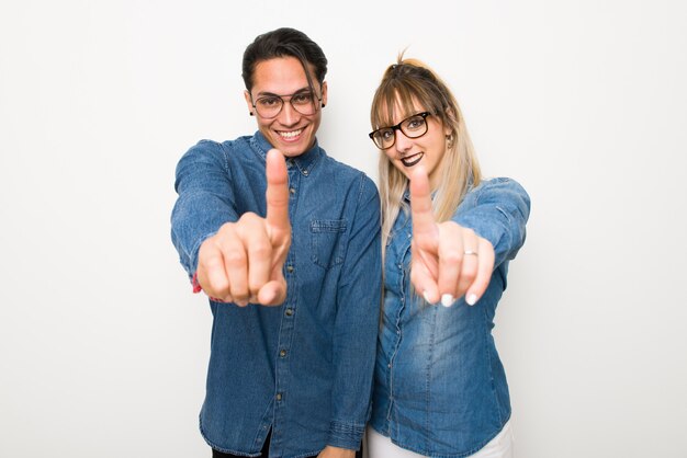 En el día de san valentín pareja joven con gafas mostrando y levantando un dedo