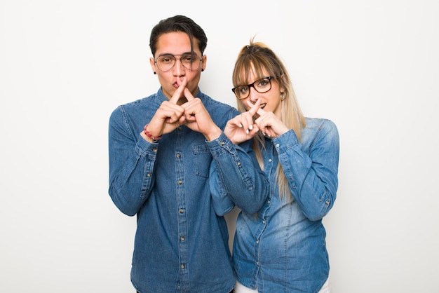 En el día de San Valentín Pareja joven con gafas que muestran un signo de gesto de silencio