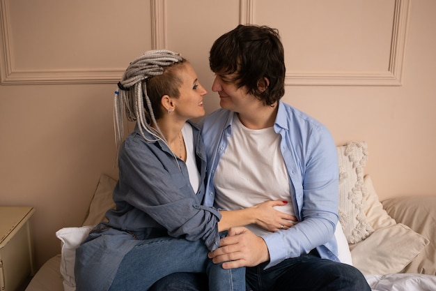 Foto dia de san valentin. pareja sentada en la cama en el dormitorio en casa. disfrutando pasar tiempo juntos.