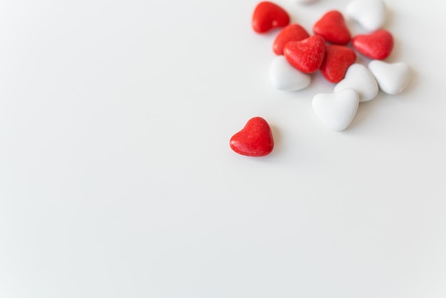 Día de San Valentín patrón de fondo plano laico vista superior de caramelos rojos y blancos en forma de corazón esparcidos sobre fondo blanco Lugar para una inscripción