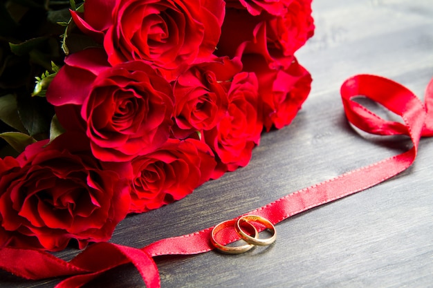 Día de San Valentín Rosas rojas y anillo de bodas un fondo de madera