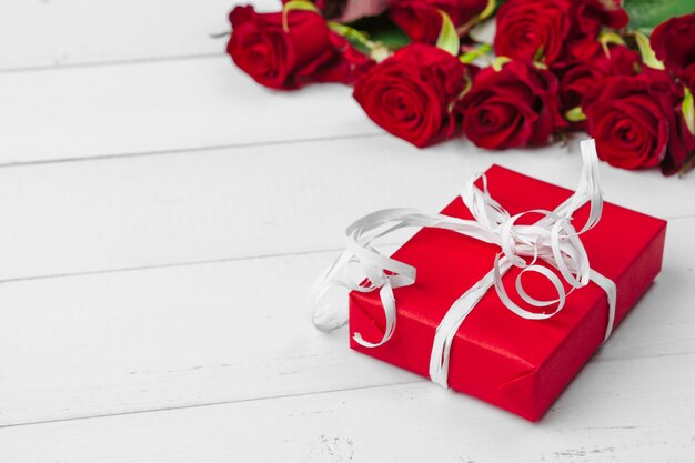 Día de San Valentín. Rosas rojas y caja de regalo en mesa de madera