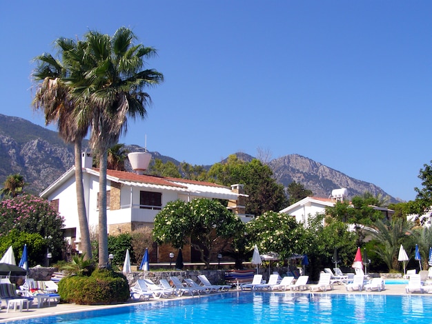 Foto día soleado en la costa mediterránea y una piscina con tumbonas y una sombrilla de playa