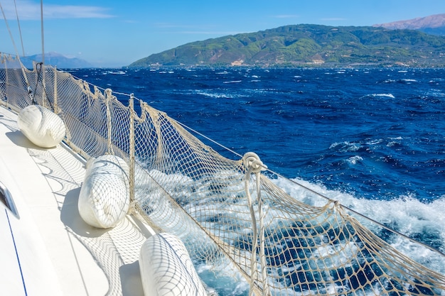 Día soleado de verano. Tiempo ventoso cerca de la costa del Golfo de Corinto. Cubierta de un velero blanco con defensas