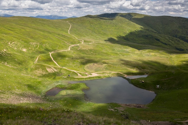 Un día soleado en un verde prado de montaña con el lago Svydovets Los Cárpatos