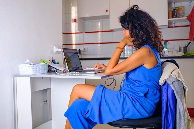 Día de trabajo en la oficina en casa. La chica trabaja detrás de una laptop en casa con auriculares y una taza de café.