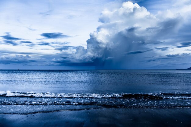 El día de verano antes del atardecer fluye a través de las nubes con olas que llegan a la playa