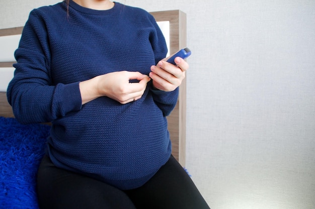 Diabetes gestacional Una mujer embarazada mide su azúcar en sangre en casa con un glucómetro
