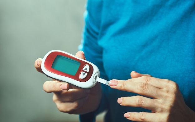 Diabetische Frau mit Blutzuckermessgerät, weibliche Hände halten Lanzettenstift-Glukometer am Finger messen Zucker-Check-Insulin