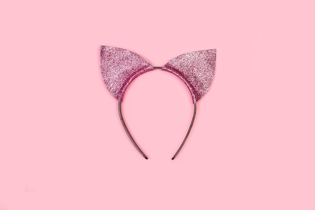 Una diadema con forma de oreja felina sobre un fondo rosa con espacio para copiar