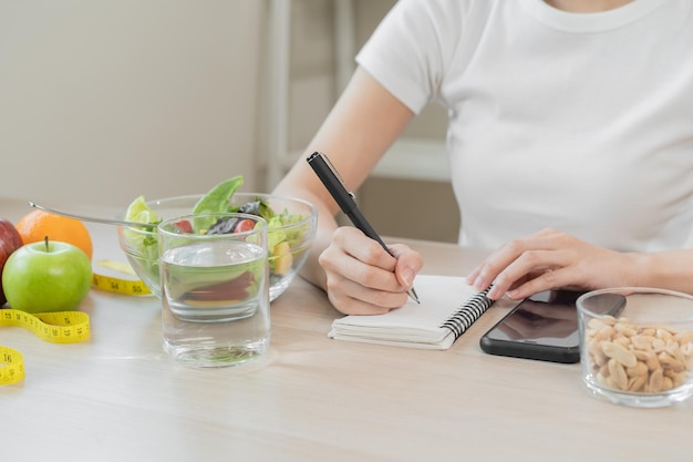 Diät Diätende Hand der asiatischen jungen Frau, die arbeitet, schreiben Diätplan, richtige Ernährung mit frischem Gemüse essen, Salat ist Nahrung für eine gute Gesundheit, essen keine Junk-Food Ernährungsberaterin, weiblich, Gewichtsverlust von gesund