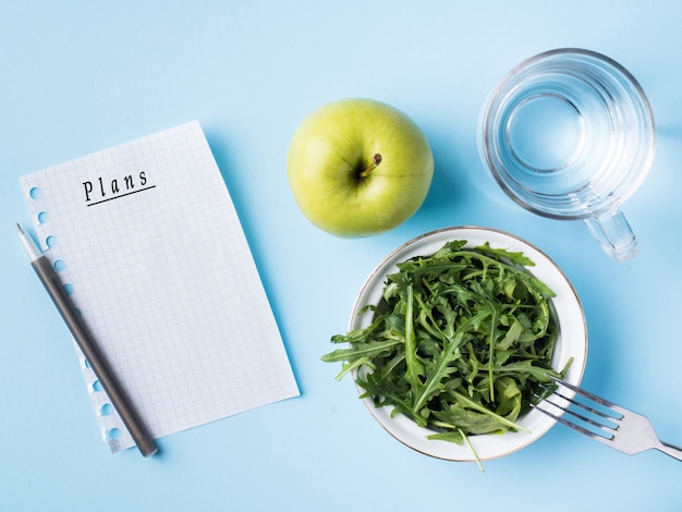 Diät lässt Salatgrün Apple ein Glas Wasser auf blauem Hintergrund.