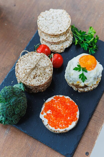 Diät-Reisbrot Kirschtomaten und frischer Kaviar und Petersilie auf dunklem Hintergrund Snack-Brot Blick von oben Ballaststoffe Gesundes Essen