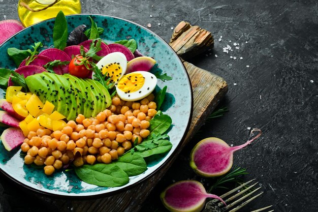 Diät-Salat Kichererbsen Spinat Radieschen Avocados und Eier Schüssel Buddha Veganes Essen Draufsicht Auf einem Steinhintergrund