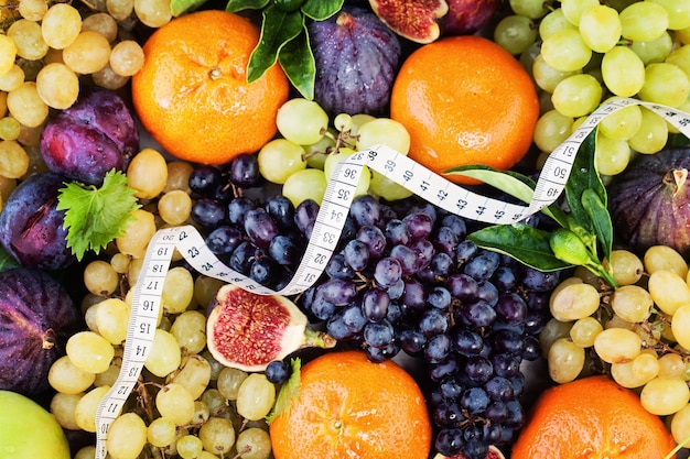 Diät- und Fitness-Hintergrund mit bunten Früchten und Maßband