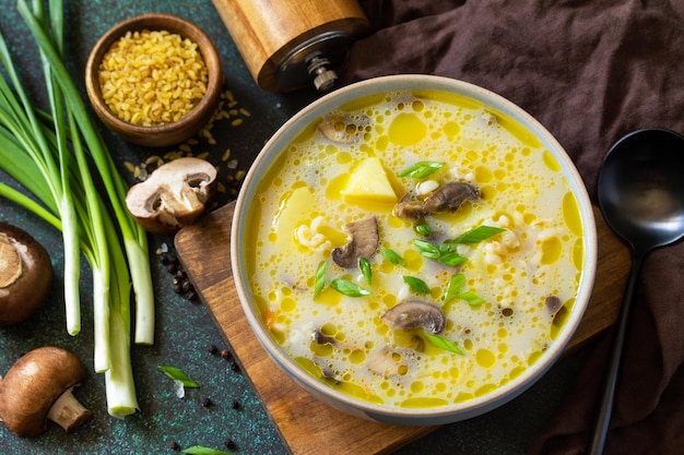 Diät- und gesundes Ernährungskonzept Königliche Pilzcremesuppe mit Bulgur auf dunklem Steinhintergrund