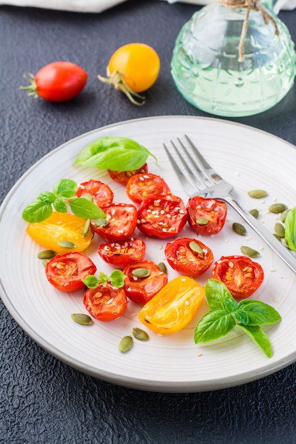 Diät-vegetarischer Snack. Sonnengetrocknete Tomaten mit Basilikum, Sesam und Kürbis auf einem Teller auf schwarzem Hintergrund. Vertikale Ansicht