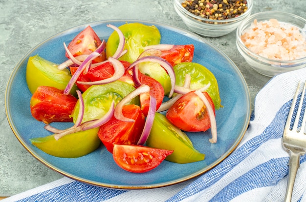 Diätessen. Salat aus Scheiben von frischen hellen Tomaten und Zwiebeln. Studiofoto.