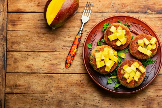 Diätetische vegane Quinoa-Koteletts mit Mango auf ländlicher Holzoberfläche. Platz für Text