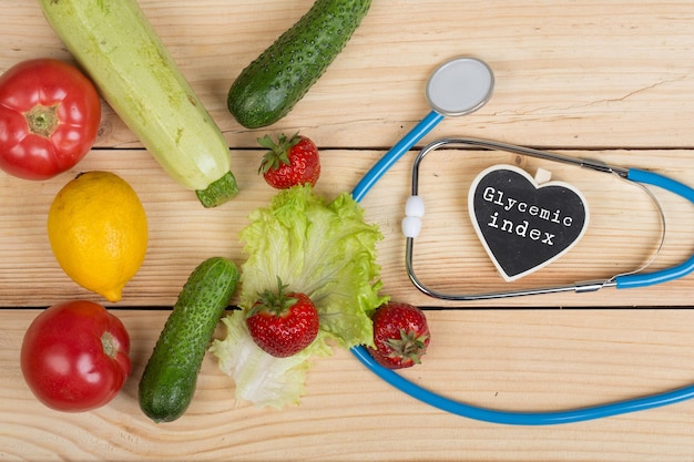 Diätkonzept Tafel in Herzform mit Text Glykämischer Index Stethoskop Gemüse Obst und Beeren